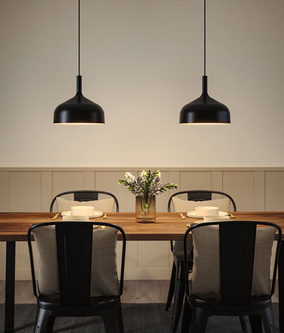 Zwei schwarze Metall-Hängeleuchten über Holztisch mit gedecktem Platz und Blumenvase im Esszimmer
