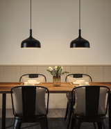 Zwei schwarze Metall-Hängeleuchten über Holztisch mit gedecktem Platz und Blumenvase im Esszimmer