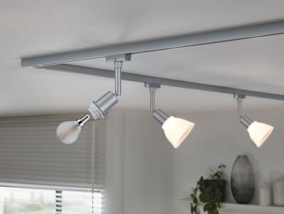 Zilveren LED-rails met drie verstelbare spots in moderne woonkamer met planten.