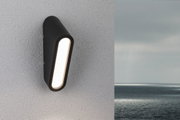 Schwarze LED-Wandleuchte aus Metall mit länglichem Leuchtfeld an weißer Außenwand mit Meerblick