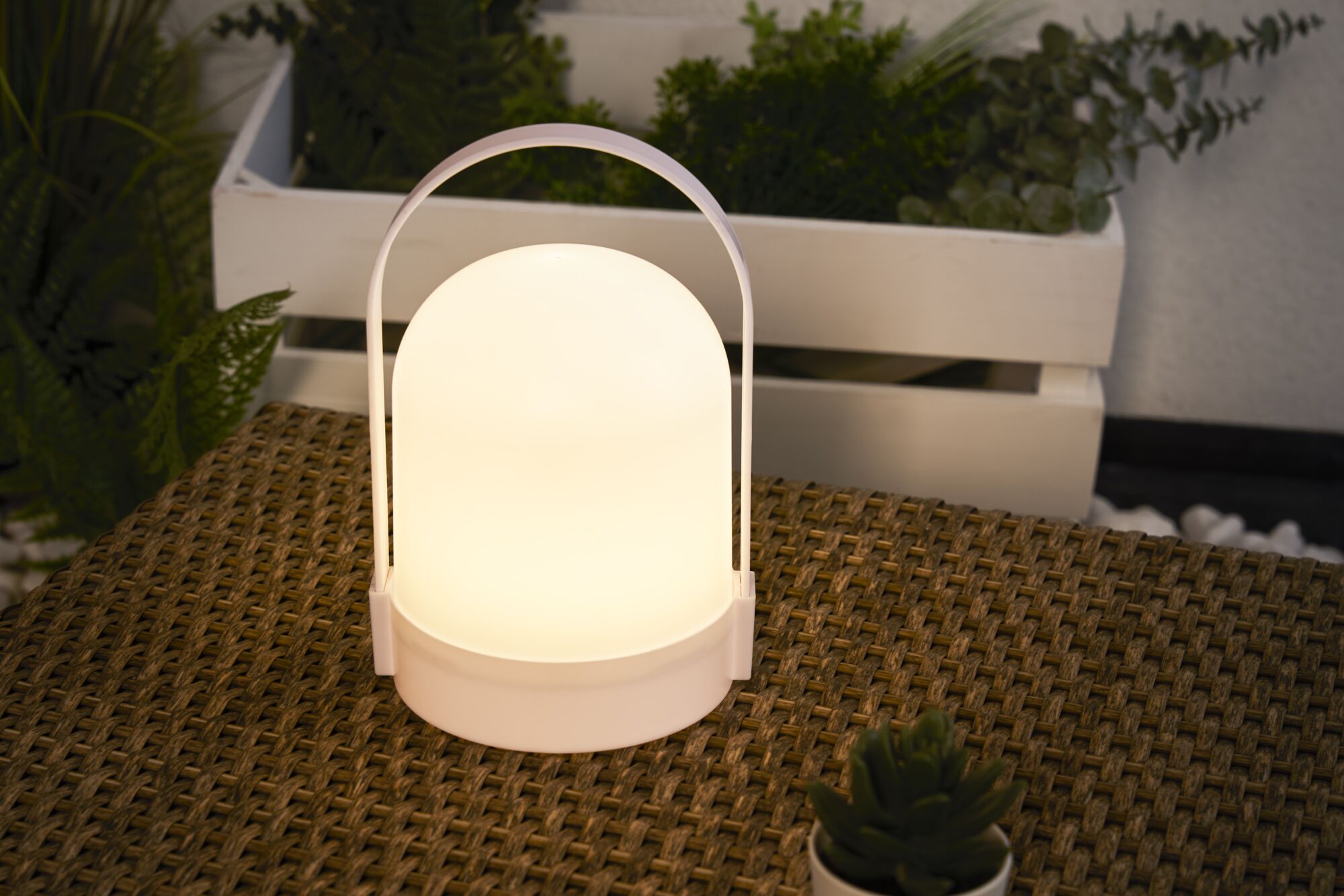 Witte draagbare LED-tafellamp met warm wit licht op gevlochten tafel voor sfeervolle verlichting.