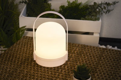 Witte draagbare LED-tafellamp met warm wit licht op gevlochten tafel voor sfeervolle verlichting.