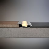 Zilverkleurig aluminium LED-vloerprofiel met warm wit licht tussen hout- en stenen vloer