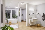 Modernes Badezimmer mit weißer Badewanne, Holzfußboden und runden Deckenleuchten in Weiß für Wohnraumbeleuchtung