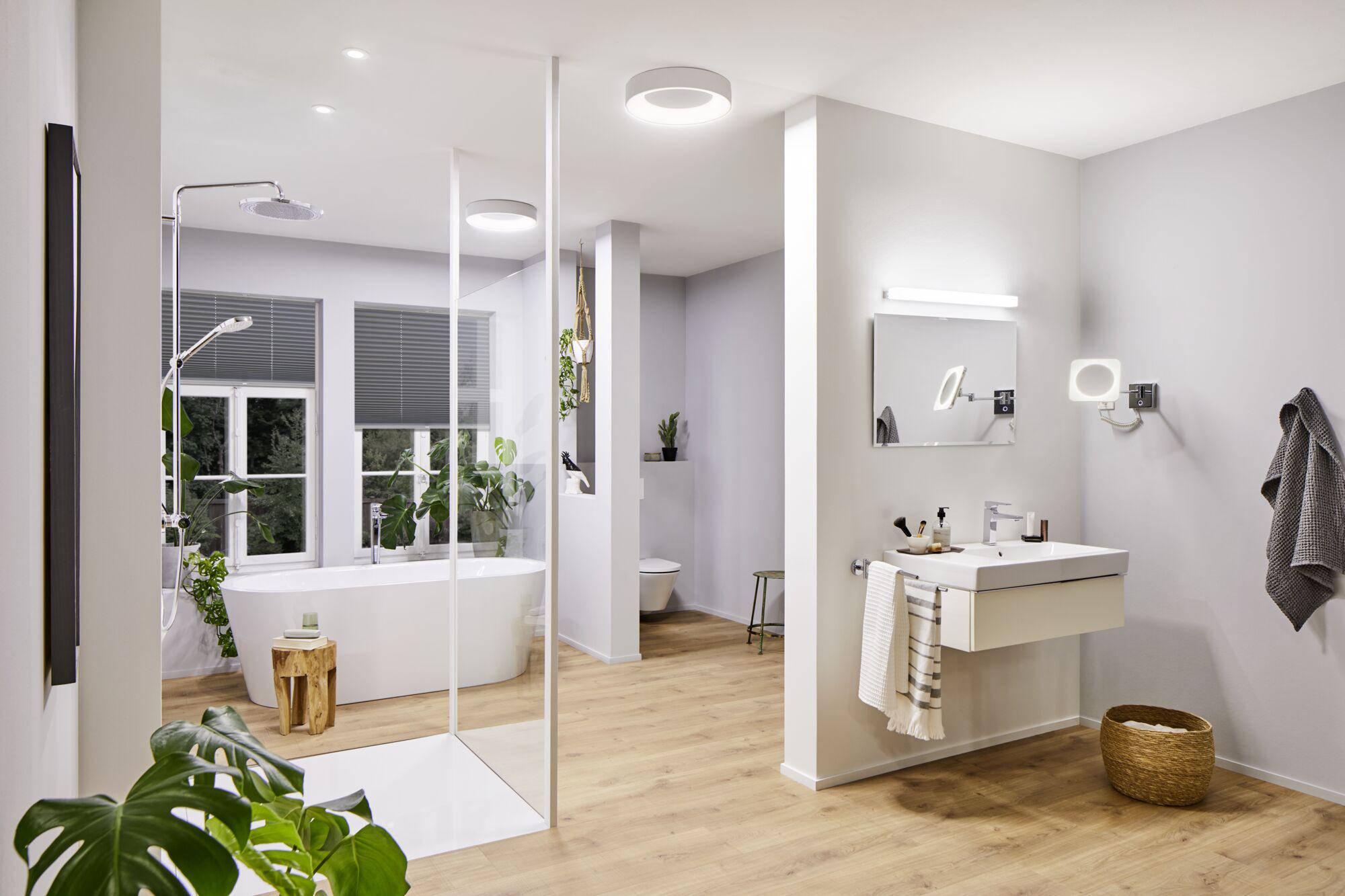 Modern bathroom with white bathtub, wooden floor and round white ceiling lights
