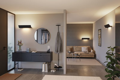 Salon moderne avec applique murale noire, canapé beige et entrée élégante avec miroir et porte-manteau