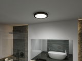 Round ceiling light with black frame and white illumination in modern bathroom with bathtub.