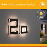 Modern black house number 2a with warm white solar light on grey wall for outdoor use