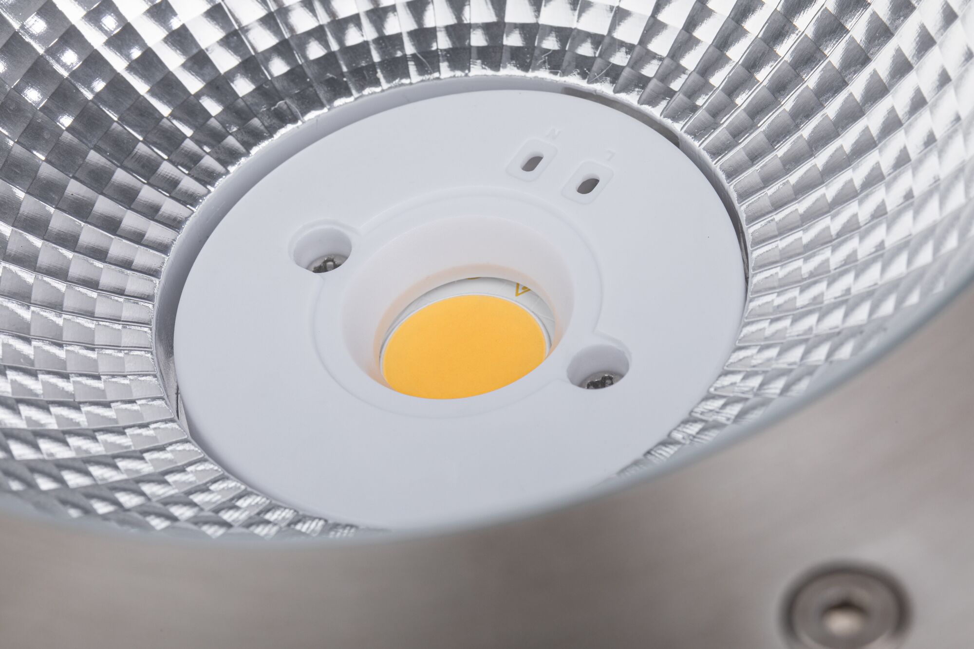 Close-up van LED-reflector met zilverkleurig aluminium oppervlak en gele lichtbron