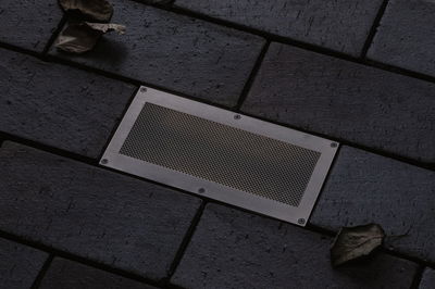 Projecteur de sol rectangulaire en acier inoxydable avec grille intégré dans pavé sombre extérieur