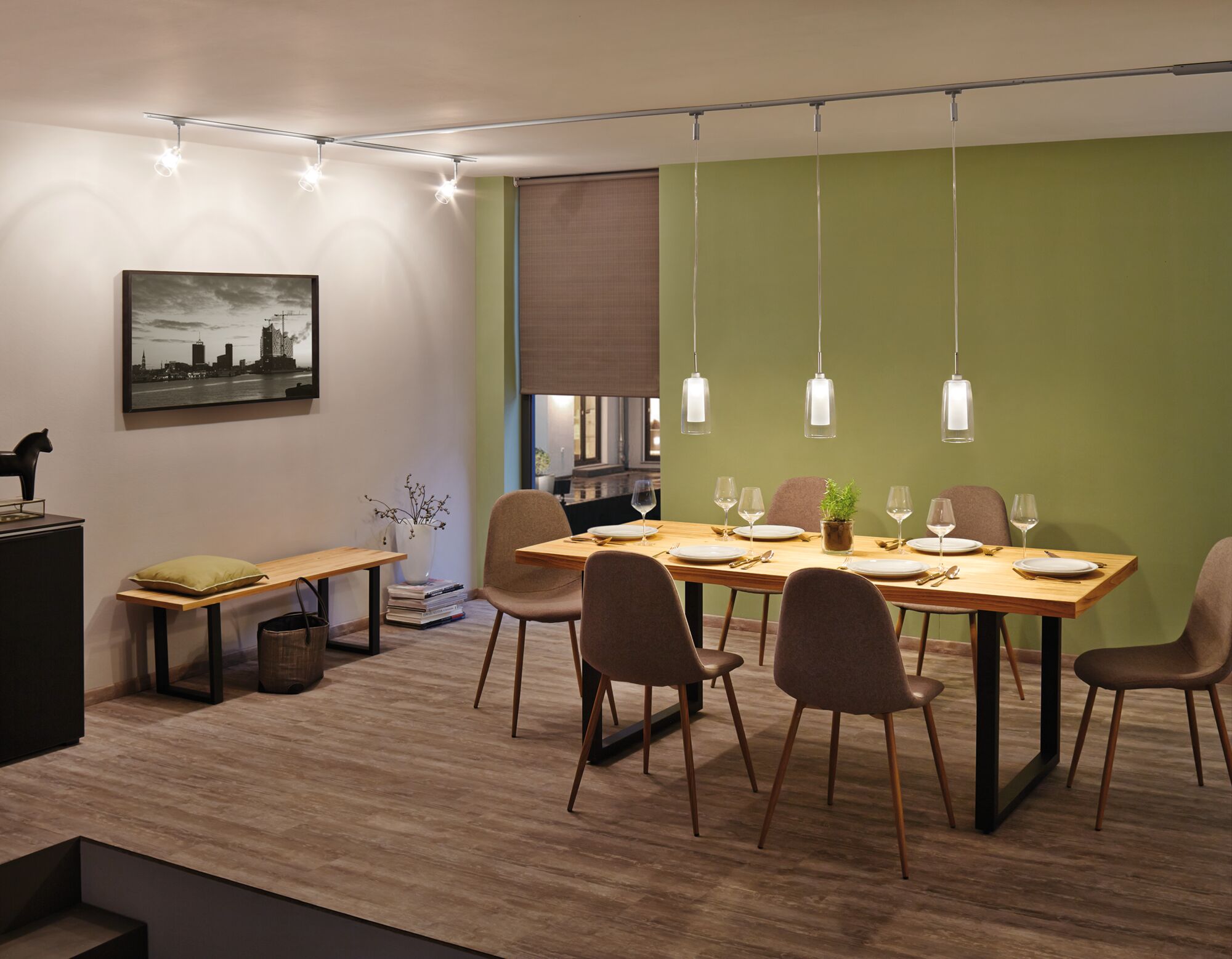 Dining room with wooden table, brown chairs and modern glass pendant lights on track system