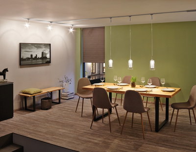 Dining room with wooden table, brown chairs and modern glass pendant lights on track system