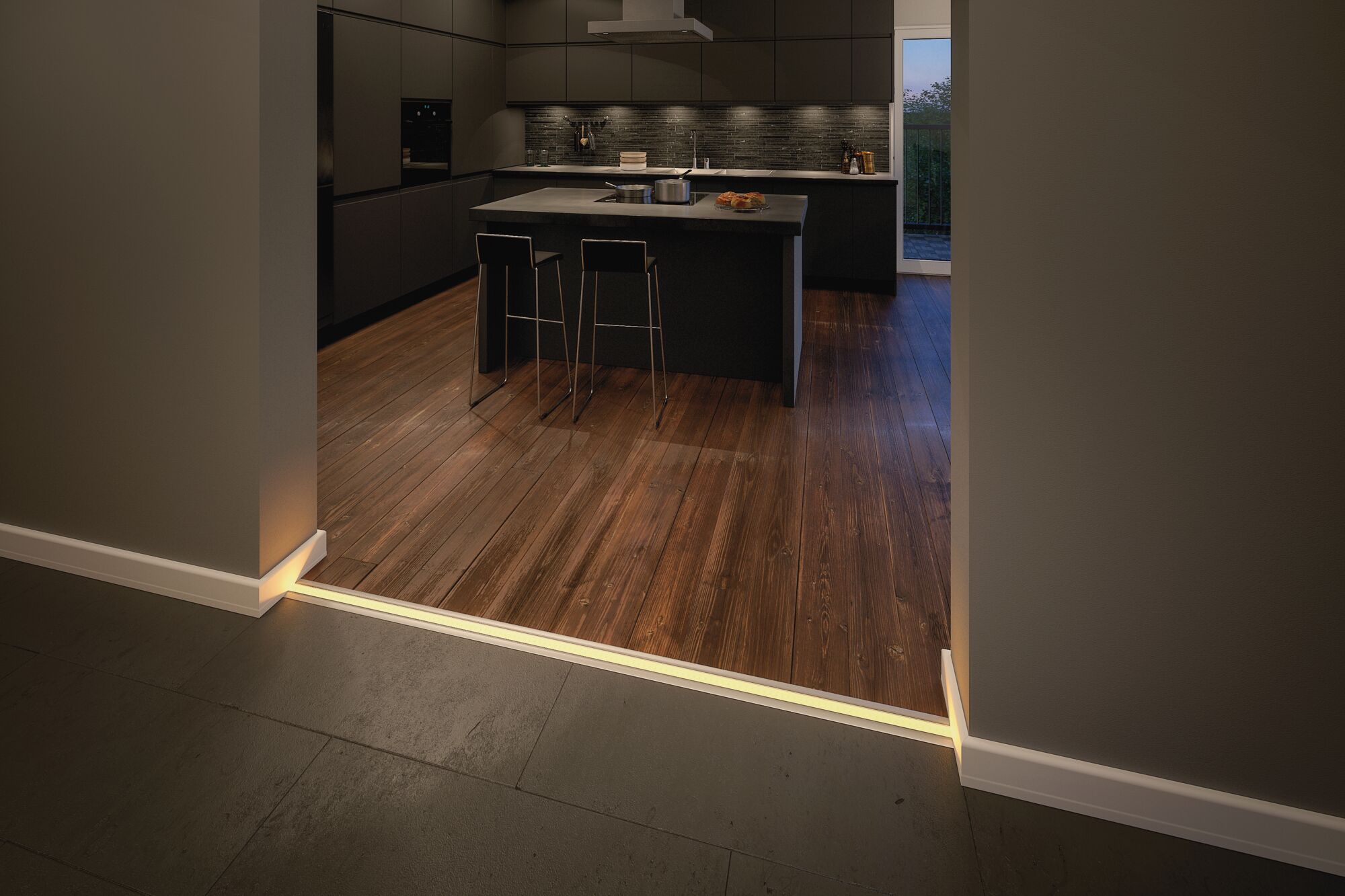 Moderne keuken met donkere kasten, houten vloer en LED-vloerverlichting bij de overgang.