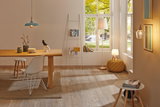 Salon lumineux avec sol en bois, table à manger, chaises blanches et lampes suspendues et sur pied modernes