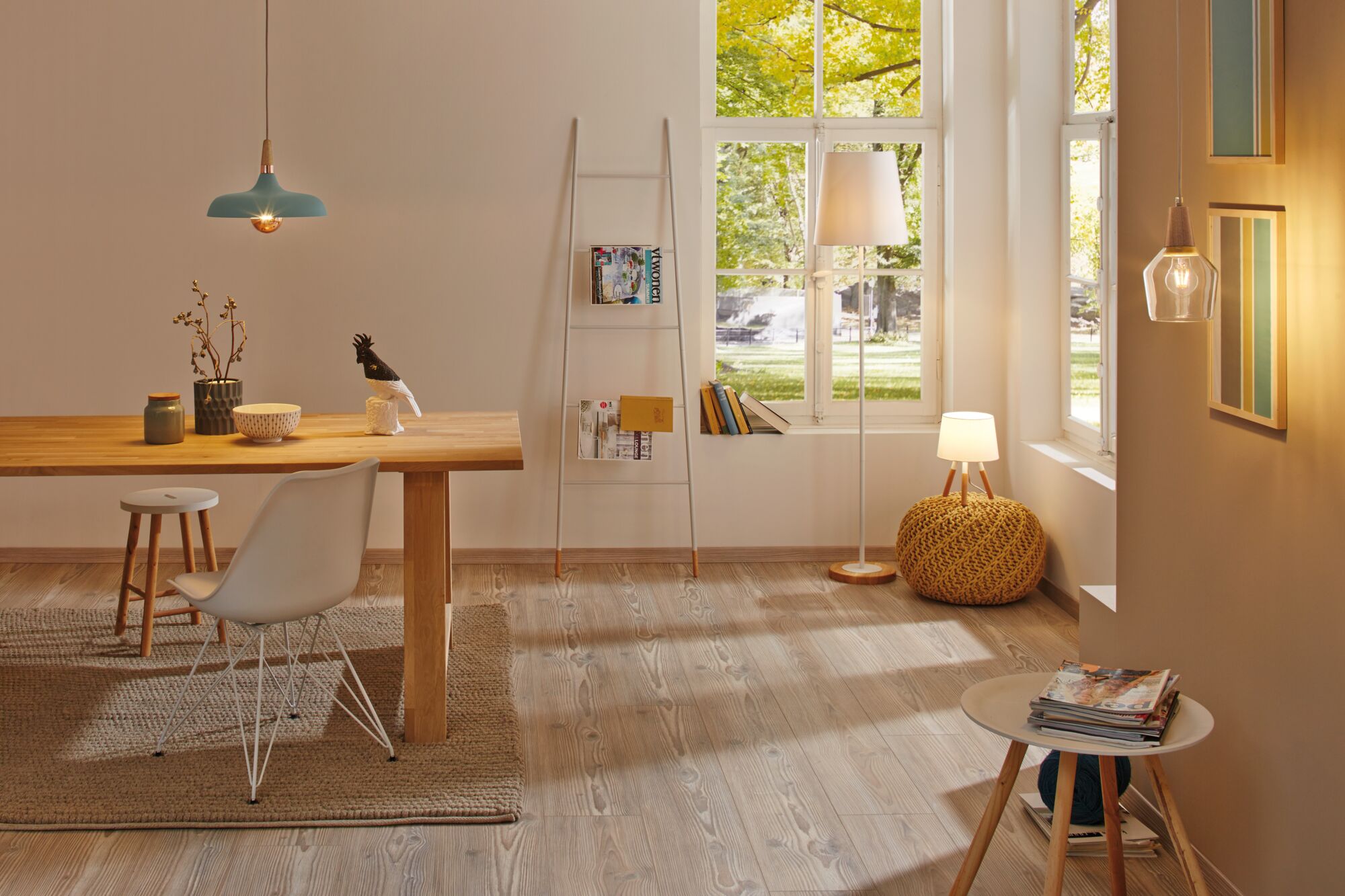 Lichte woonkamer met houten vloer, eettafel, witte stoelen en moderne hang- en vloerlampen