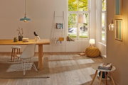 Salon lumineux avec sol en bois, table à manger, chaises blanches et lampes suspendues et sur pied modernes