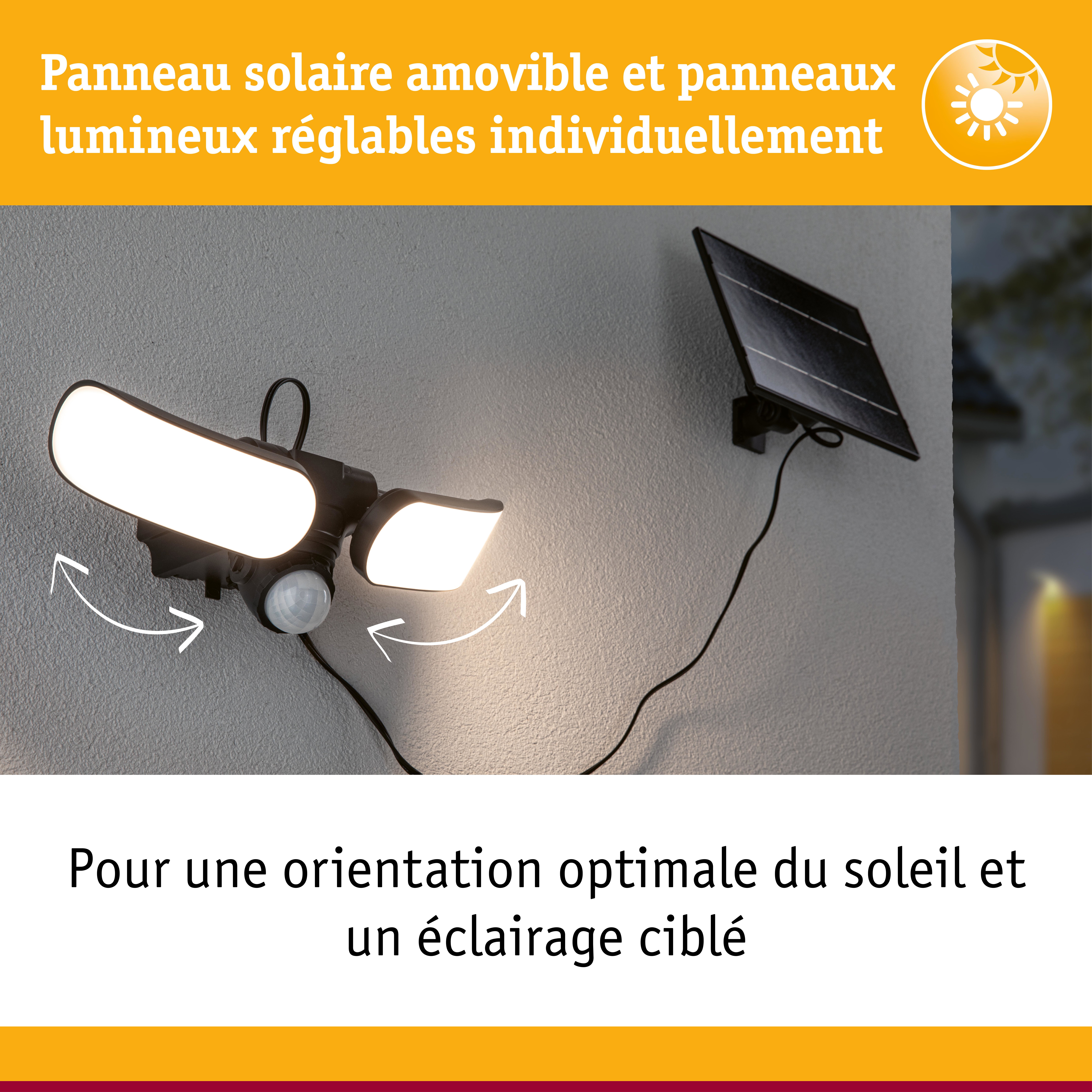 Lampe solaire noire avec panneaux LED réglables et panneau solaire fixée sur mur gris extérieur