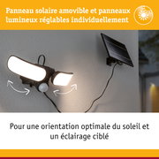 Lampe solaire noire avec panneaux LED réglables et panneau solaire fixée sur mur gris extérieur