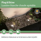 Spots LED encastrés gris métal à lumière blanche chaude dans un lit de gravier pour ambiance jardin