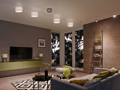 Moderne woonkamer met grijze bank, groene dressoir en plafondlamp met stoffen lampenkappen