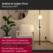 Lampadaire avec structure métallique noire et deux globes lumineux blancs à côté d'un fauteuil blanc et plante