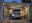 Beleuchteter Carport mit moderner LED-Deckenbeleuchtung und Mann, der Auto mit geöffneter Motorhaube wartet.