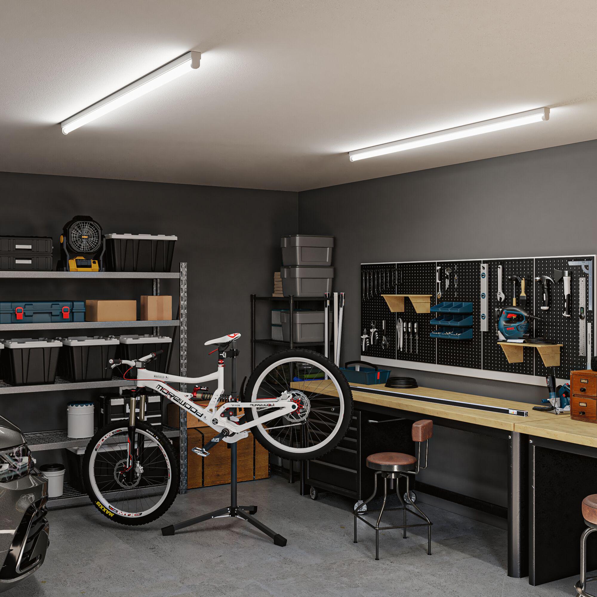 Werkstatt mit weißen LED-Röhren an der Decke, Arbeitsbank, Werkzeugwand und Fahrrad in Reparatur