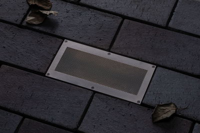 Rechteckiger Edelstahl-Bodenstrahler mit Gittereinsatz in dunklem Pflaster für Außenbeleuchtung.