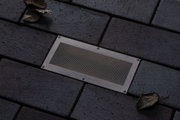 Ingebouwde roestvrijstalen vloerlamp met gaas inzet op donkere bestrating voor buitenverlichting