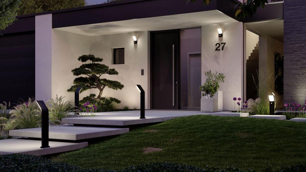 Moderne buitenverlichting met zwarte LED-padverlichting en wandlampen bij huis met tuin.