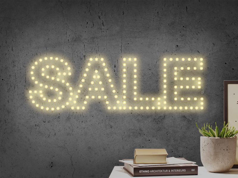 Oplyst SALE-skilt med varm hvid LED-lys på grå væg til salgsfremmende kampagner.