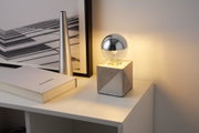 Moderne bordlampe i beton med sølvpære på hvidt skab til stemningsbelysning
