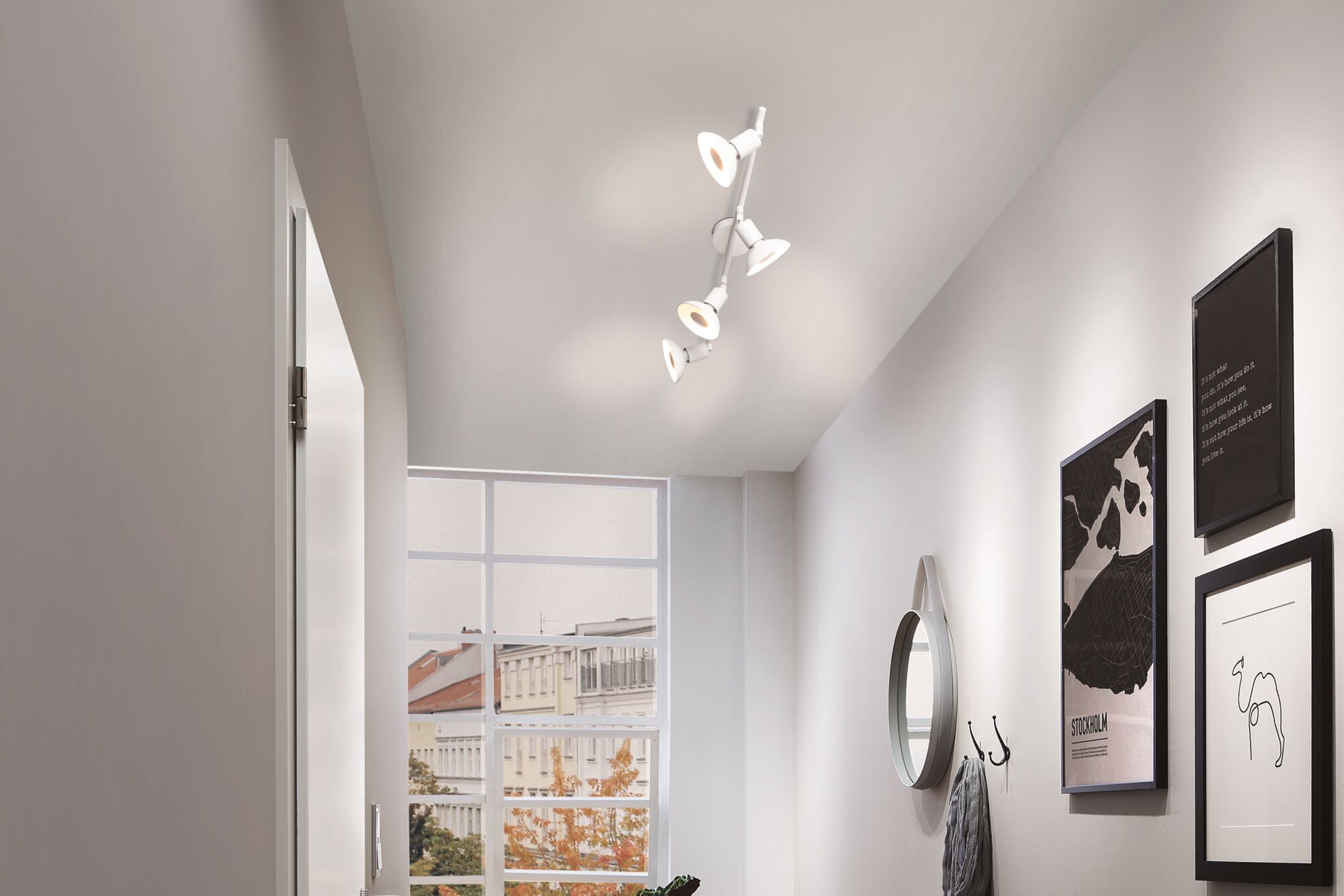 Moderne witte plafondspot met vier verstelbare lampen in lichte gang met raam en wanddecoratie