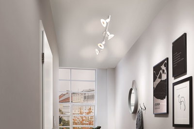 Modern white ceiling spotlight with four adjustable lamps in bright hallway with window and wall decor