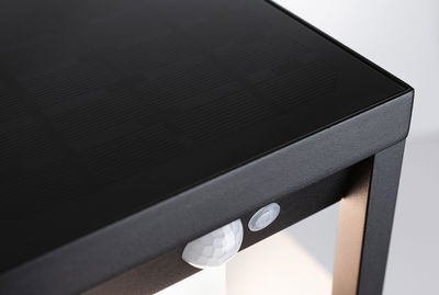 Black solar light housing with integrated motion sensor and matte metal frame for outdoor lighting