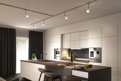 Modern white kitchen with wooden countertop and adjustable LED track lights on ceiling.
