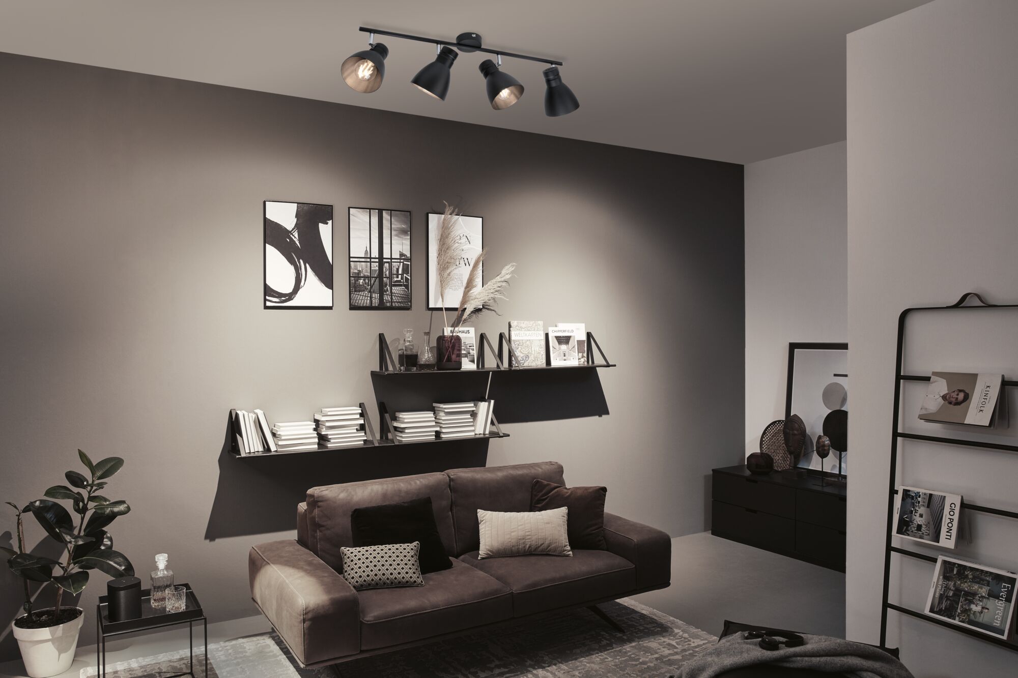 Schwarze Deckenleuchte mit vier verstellbaren Spots in modernem Wohnzimmer mit braunem Sofa.