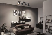 Schwarze Deckenleuchte mit vier verstellbaren Spots in modernem Wohnzimmer mit braunem Sofa.