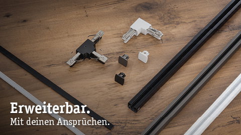 Black and white metal URail tracks and connectors on wood surface for modular lighting systems.