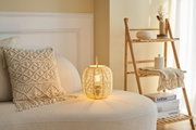 Coin salon confortable avec canapé crème, coussin macramé et lampe en rotin pour décoration chaleureuse