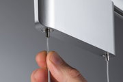 Hand zieht dünnes Stahlseil aus silbernem Aluminiumgehäuse für LED-Hängeleuchte, Beleuchtung Zubehör