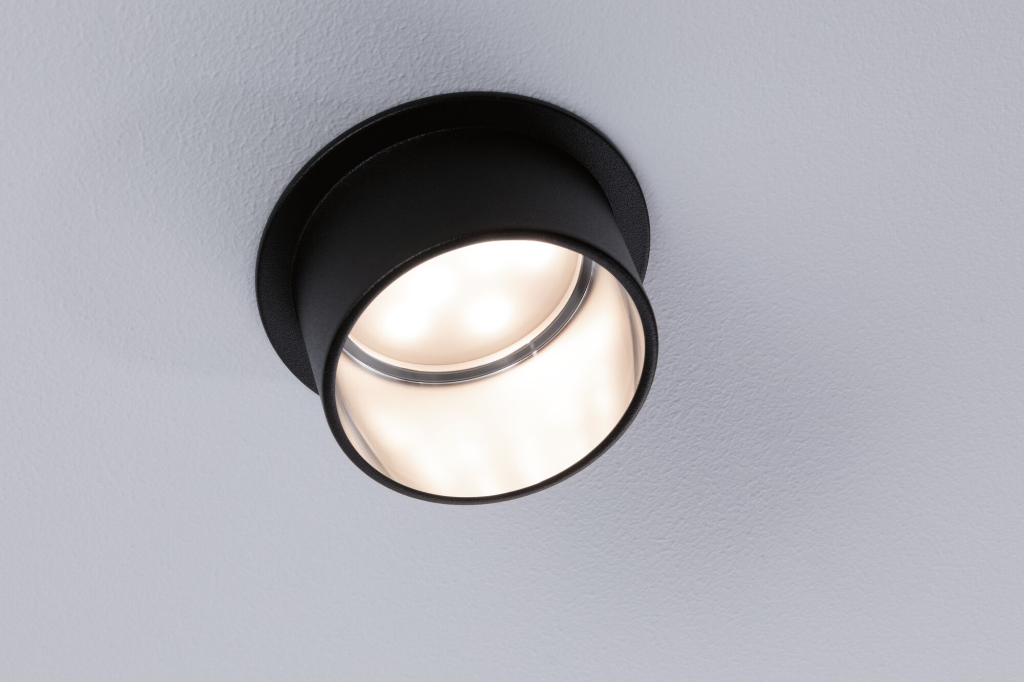 Zwarte ronde LED-plafondspot van metaal met warm wit licht voor moderne interieurs.