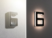 Moderne LED-væglampe formet som tallet 6 i hvid og sort med varmt indendørs lys