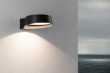 Modern black aluminum wall light with warm white LED on exterior wall overlooking the sea