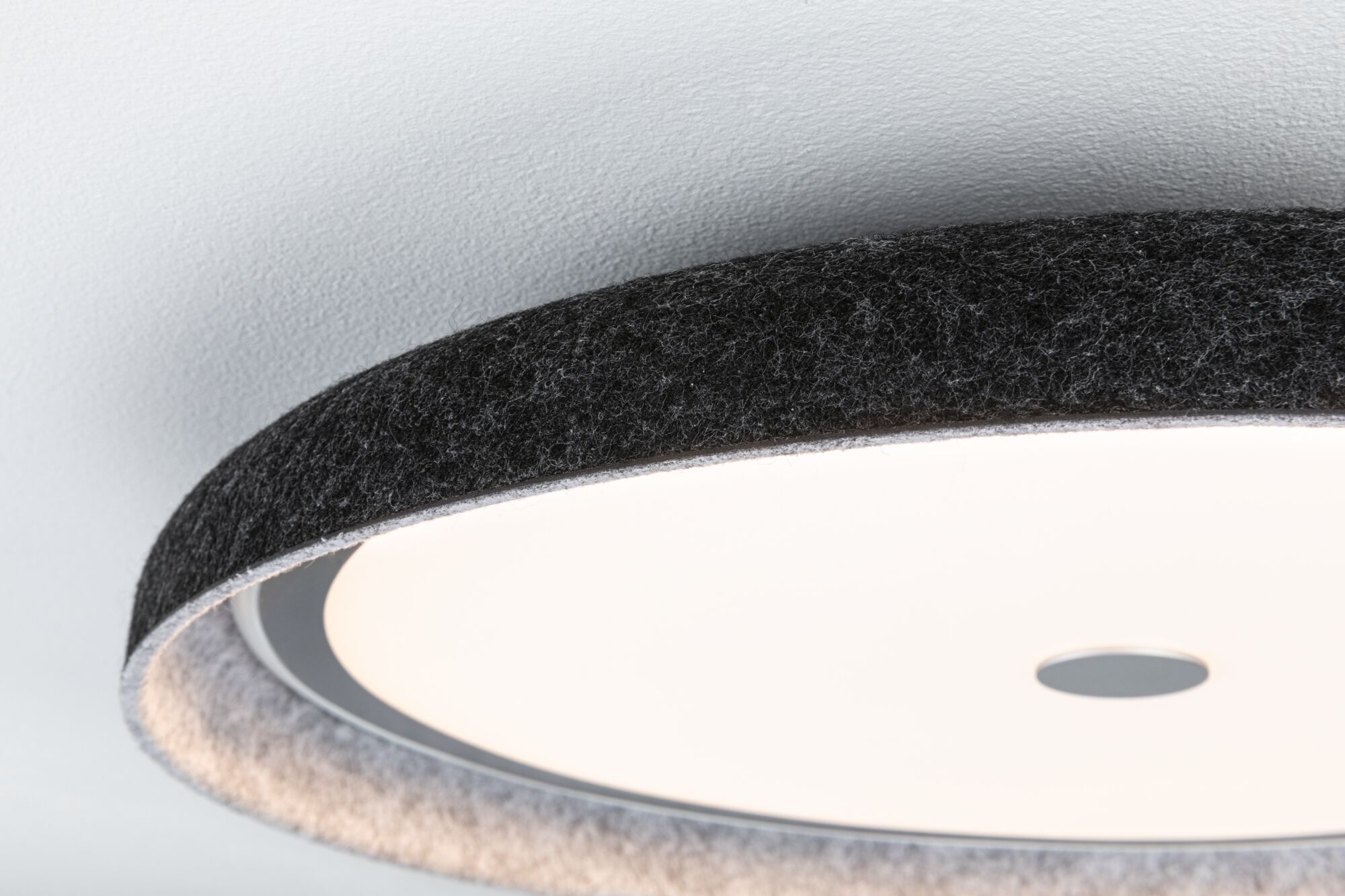 Round ceiling light with black felt edge and white diffuser for modern interior lighting.