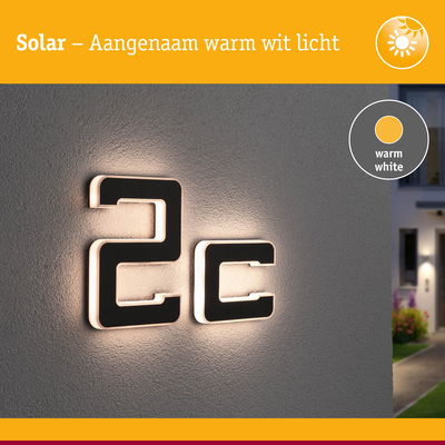 Moderne huisnummer 2c zwart met warm wit LED-licht aan grijze muur buiten