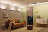 Salon moderne avec canapé en cuir marron, tapis, buffet blanc, éclairé par des spots LED au plafond