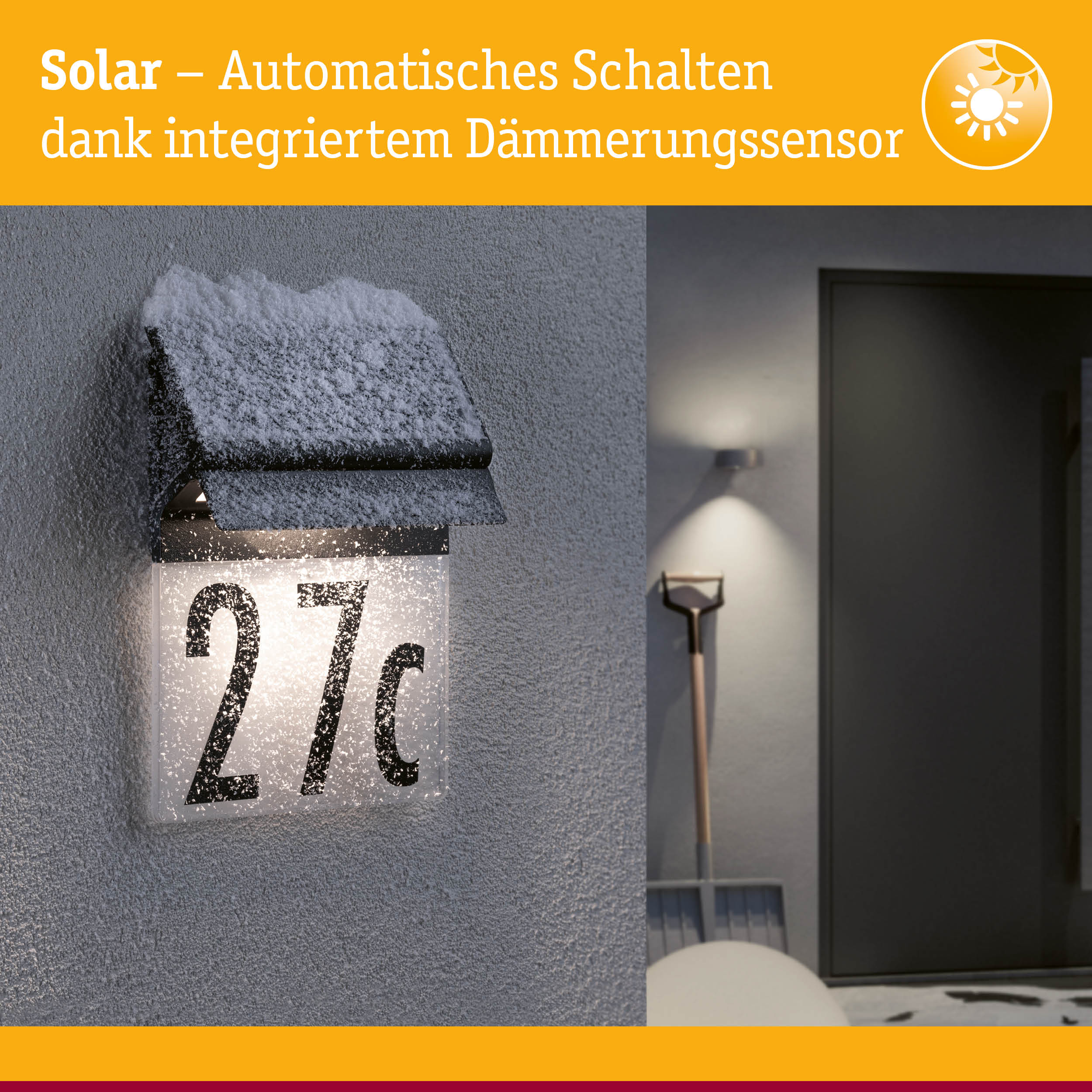 Schwarze Solar-Hausnummernleuchte mit integriertem Dämmerungssensor und Schneebedeckung an grauer Wand
