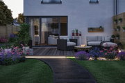 Modern garden with lit pathway, grey polyrattan furniture, and colorful flowers in outdoor living space.