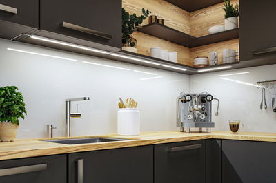 Moderne Küche mit Holzarbeitsplatte, Edelstahl-Spültischarmatur und LED-Unterbauleuchten für optimale Beleuchtung